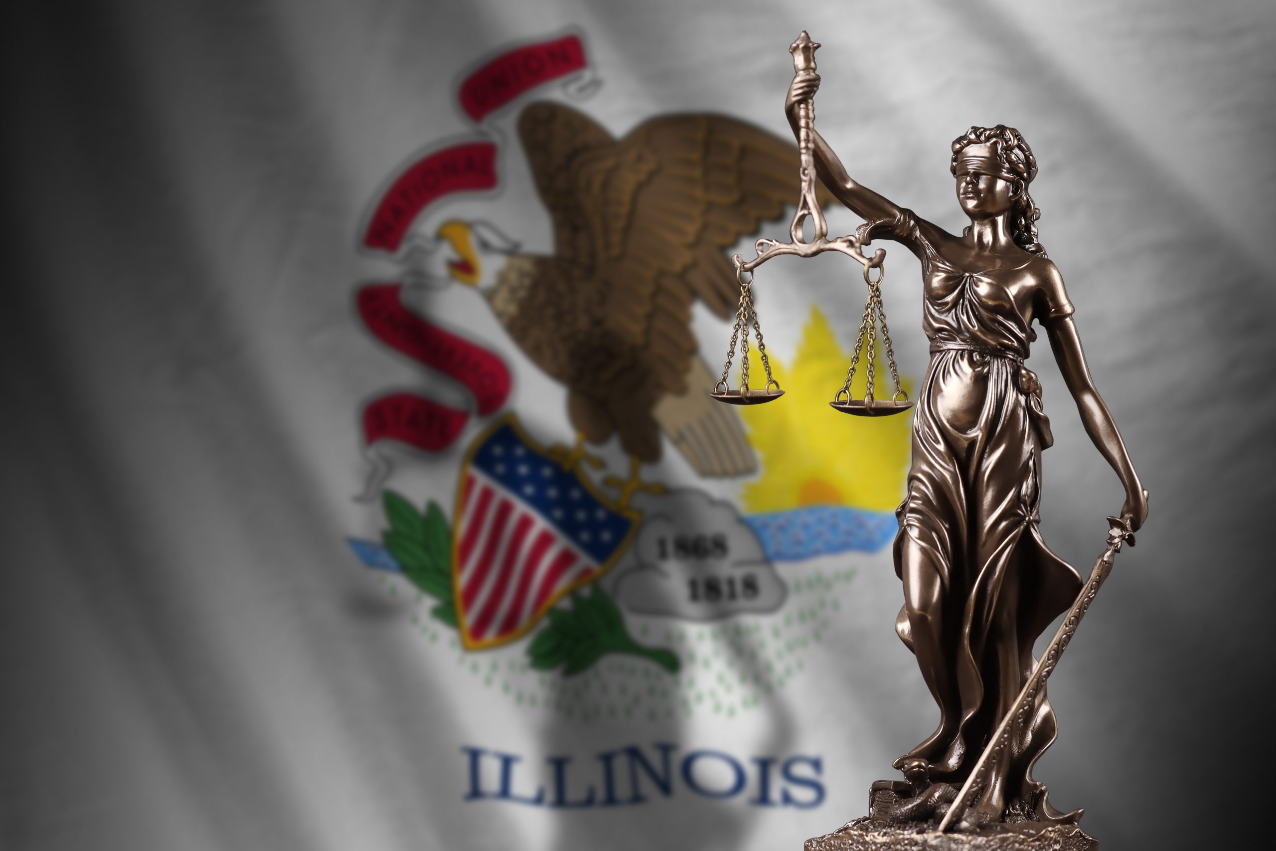 Illinois US state flag with statue of lady justice and judicial scales in dark room.